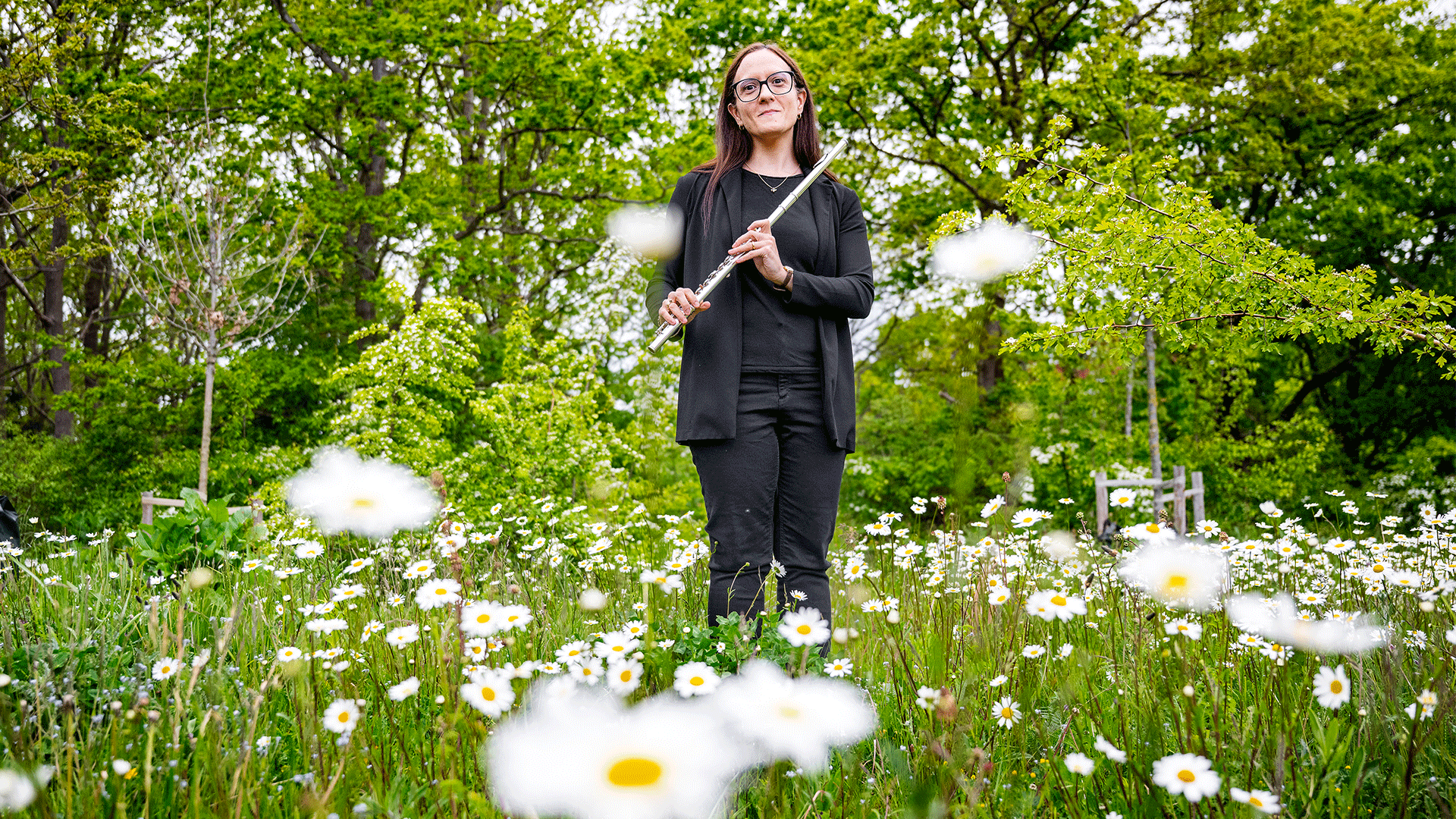 DTU professor Maria Montanucci standing in a meadow with daisies holding a flute.